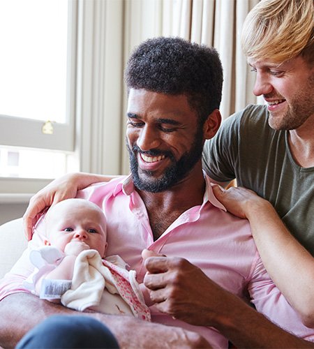 Gay couple holding their baby delivered via surrogacy